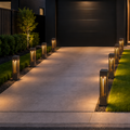 Modern house exterior with a driveway and illuminated lamp posts.